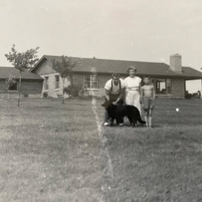 Black and white photo of family standing in yard of home