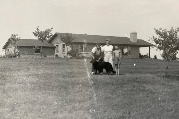 Black and white photo of family standing in yard of home