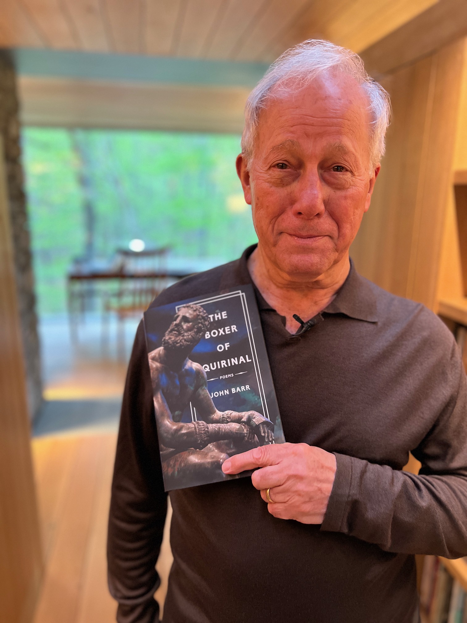 Photo of John Barr, a man, holding his book, The Boxer of Quirinal, in front of his chest