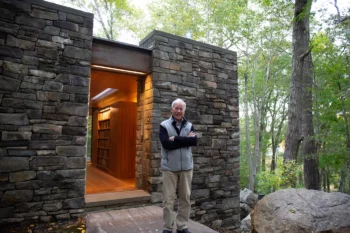 White man with white hair standing in front of a writing studio